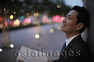 Asia Images Group - Mature man leaning against the wall smiling at night