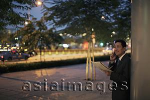 Asia Images Group - Mature man holding a newspaper and talking on the phone outdoors