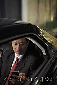 Asia Images Group - Mature man sitting in car texting on phone