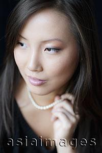 Asia Images Group - Head shot of a woman holding a pearl necklace