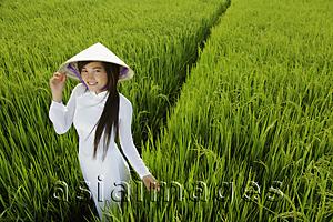 Asia Images Group - Young woman wearing traditional Vietnamese outfit standing in rice paddy