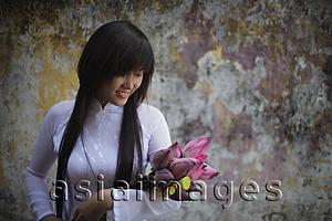 Asia Images Group - Young woman wearing traditional Vietnamese outfit holding lotus flowers