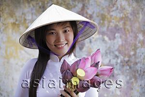 Asia Images Group - Young woman wearing traditional Vietnamese outfit holding Lotus flowers
