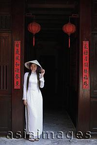 Asia Images Group - Young woman wearing traditional Vietnamese outfit standing in front of a temple, Vietnam