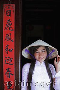Asia Images Group - Young woman wearing traditional Vietnamese outfit standing next to a temple door