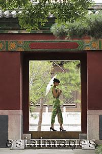 Asia Images Group - Young woman walking through a Chinese doorway holding an umbrella