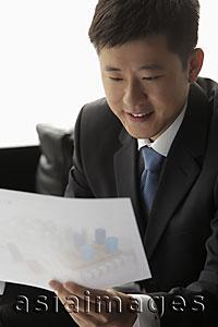 Asia Images Group - Young man in suit looking at a piece of paper