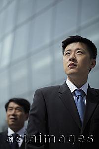 Asia Images Group - Young man wearing a suit looking up, mature man in background