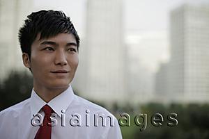 Asia Images Group - Head shot of man wearing a tie standing in front of buildings