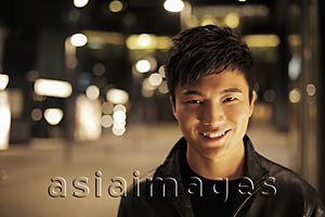 Asia Images Group - Young man smiling on the street at night