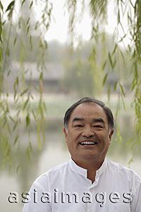 Asia Images Group - Head shot of older man smiling beneath a tree