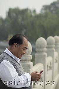 Asia Images Group - Profile of older man texting on a phone