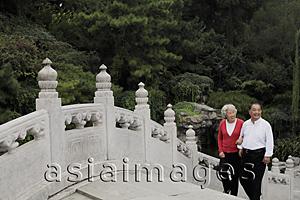 Asia Images Group - Older couple walking up an old stone bridge