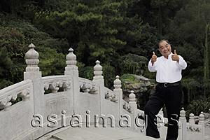 Asia Images Group - Older man standing on bridge giving thumbs up sign and smiling