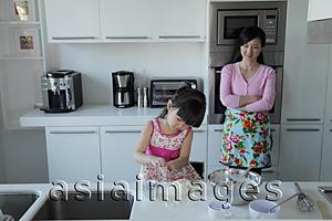 Asia Images Group - Mother watching her daughter cook in the kitchen