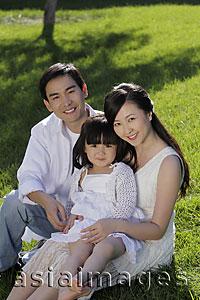 Asia Images Group - Young family sitting on the grass and smiling
