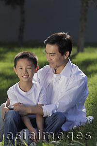 Asia Images Group - Father and son sitting on grass together