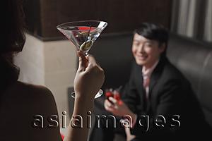Asia Images Group - Rear view of young woman holding a drink looking at a man