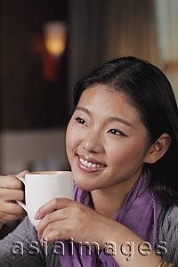 Asia Images Group - Head shot of young woman holding coffee cup