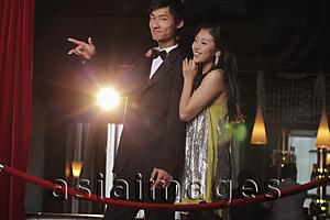 Asia Images Group - Young couple standing behind red rope at night