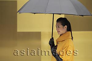 Asia Images Group - Young woman in coat and gloves holding an umbrella