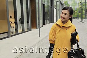 Asia Images Group - Young woman wearing coat and gloves, shopping outdoors