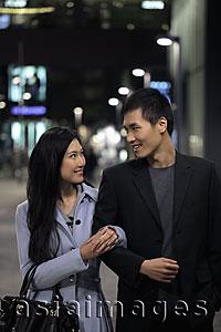 Asia Images Group - Young couple walking together on the street at night