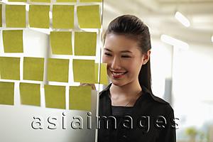 Asia Images Group - Young woman looking at stick on notes