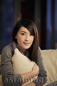 Asia Images Group - Young woman holding a pillow and smiling