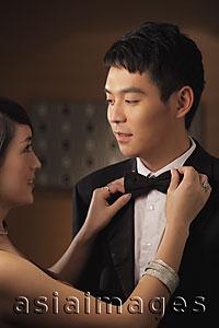 Asia Images Group - Young woman straightening a young man's bow tie