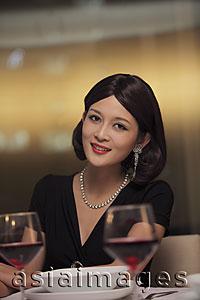 Asia Images Group - Young woman wearing diamond jewelry sitting at table
