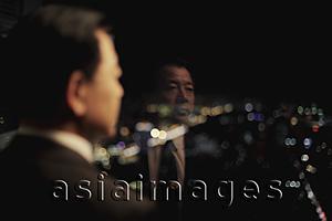 Asia Images Group - Businessman looking out of window at night