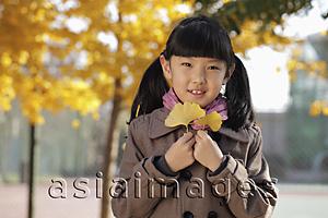 Asia Images Group - Young girl holding Autumn leaves outdoors
