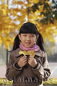 Asia Images Group - Young girl smiling and holding Autumn leaves outdoors