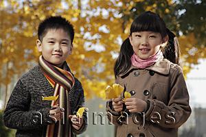 Asia Images Group - Young boy and girl holding Autumn leaves outdoor