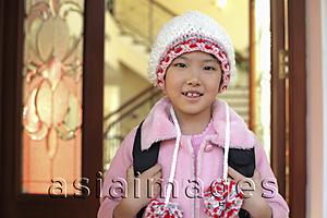 Asia Images Group - Young girl leaving her home in knitted cap and pink coat