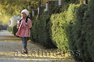 Asia Images Group - Young girl walking down sidewalk wearing pink coat, hat and backpack