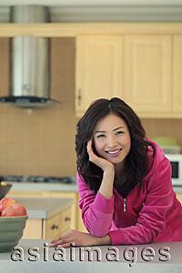Asia Images Group - Young woman wearing pink smiling in her kitchen