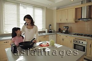 Asia Images Group - Mother and daughter cooking food together in the kitchen