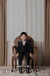 Asia Images Group - Young boy wearing suit sitting on nice chair
