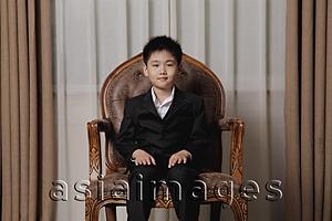 Asia Images Group - Young boy dressed up in suit sitting on a nice chair