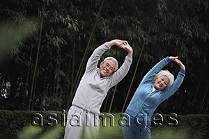 Asia Images Group - Older man and woman stretching together outdoors