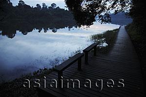 Asia Images Group - Wooden benches by edge of lake surrounded by trees in the evening