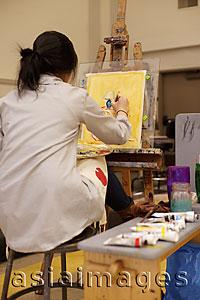 Asia Images Group - Rear view of young woman painting on an easel