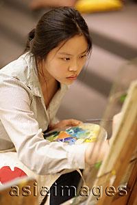 Asia Images Group - Young woman painting on an easel