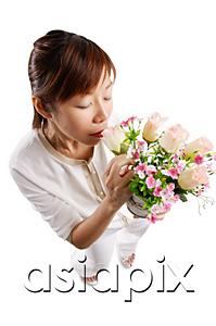 AsiaPix - Woman standing, smelling bouquet of flowers