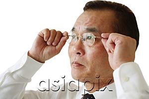AsiaPix - Businessman adjusting glasses, side view