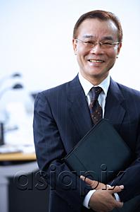 AsiaPix - Businessman with binder, looking at camera, portrait