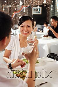 AsiaPix - Couple at restaurant, holding glasses of water, over the shoulder view