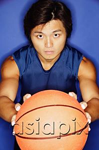 AsiaPix - Man holding basketball out towards camera